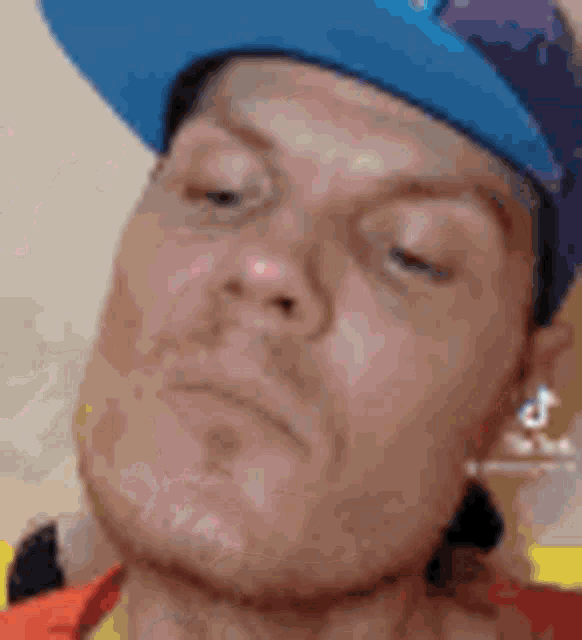 a close up of a man wearing a blue hat and making a funny face .