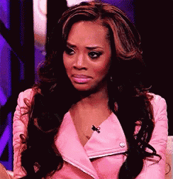 a woman with long hair is wearing a pink jacket and making a funny face .