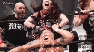 a woman in a wrestling ring with a man in a black shirt that says " all day "