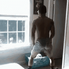a shirtless man is standing in front of a window looking out