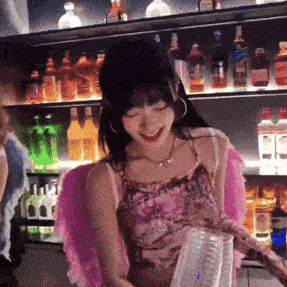 a woman wearing pink wings is standing in front of a shelf full of bottles of alcohol
