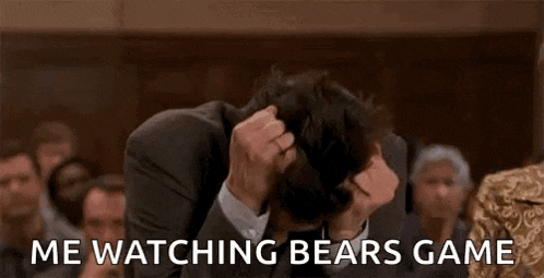 a man in a suit and tie is watching a bears game .