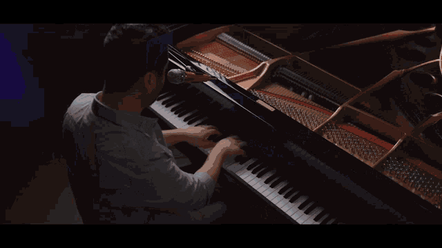 a man is playing a piano and singing into a microphone