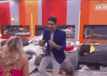 a man in a blue jacket is dancing in a messy room with a woman .