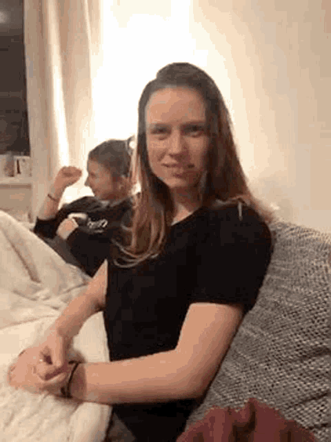a woman in a black shirt is sitting on a couch with another woman .
