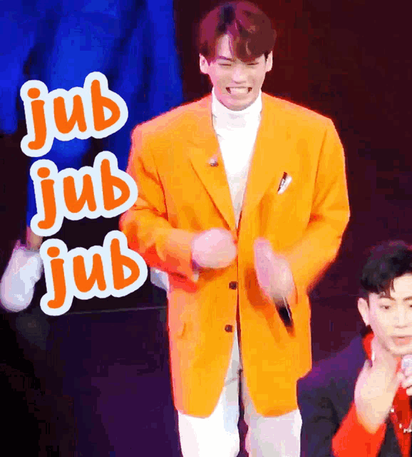 a man in an orange jacket is dancing in front of a sign that says " jub "
