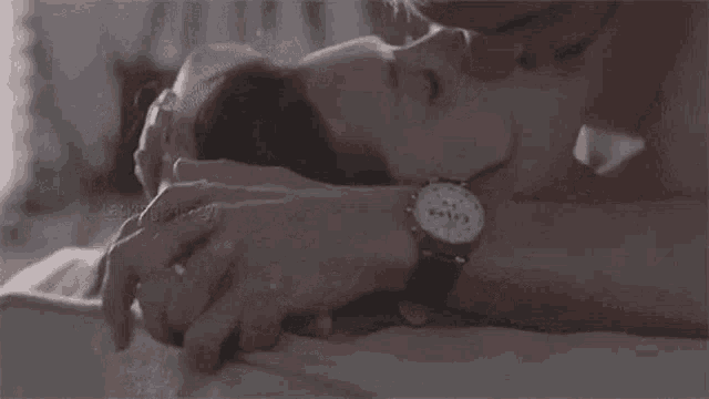a man and a woman are kissing on a bed . the woman is wearing a ring on her finger .