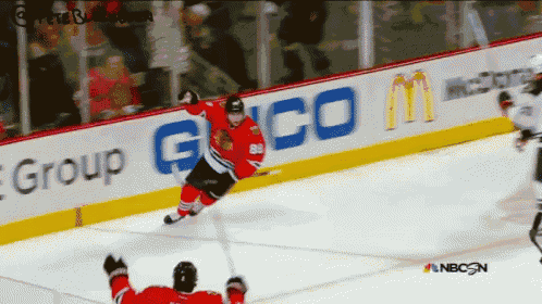 a hockey game is being played in front of an ad for geico