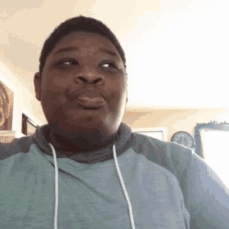a man wearing a blue hoodie is making a funny face .