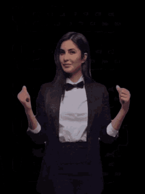 a woman in a tuxedo and bow tie is giving a middle finger