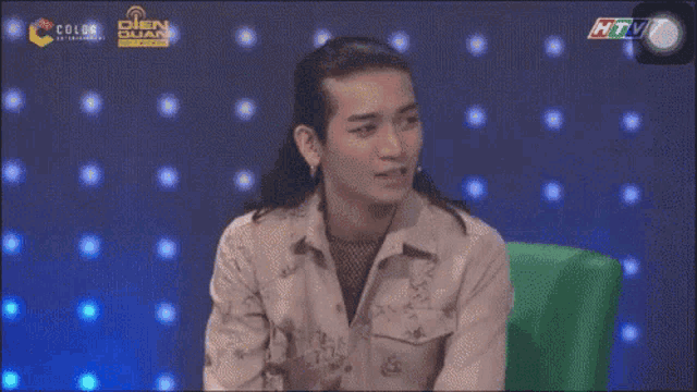 a man with long hair is sitting in front of a screen that says chôm chu