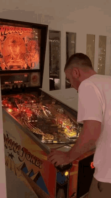 a man is playing indiana jones pinball game