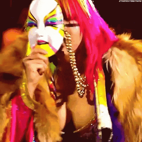 a woman with pink hair is wearing a colorful mask .