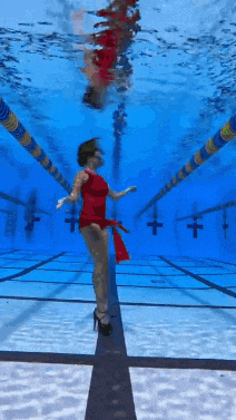 a woman in a red dress is standing in the middle of a swimming pool .