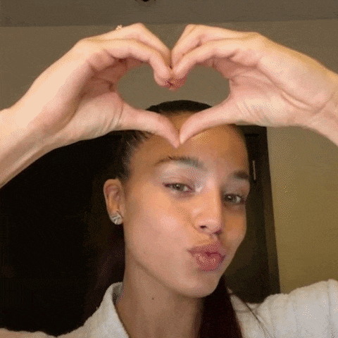 a young woman is making a heart shape with her hands .