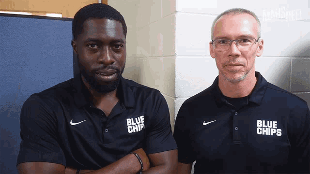 two men wearing black shirts with blue chips on them