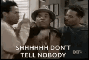 three men are standing next to each other in a room and one of them is pointing at the other .