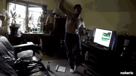 a man without a shirt is dancing in front of a computer monitor that says nokeric on the bottom