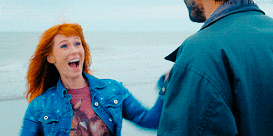 a man and a woman are standing on the beach and the man is wearing a blue jacket
