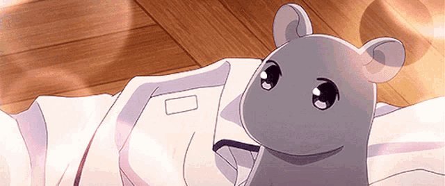 a mouse laying on a bed with a white shirt on it