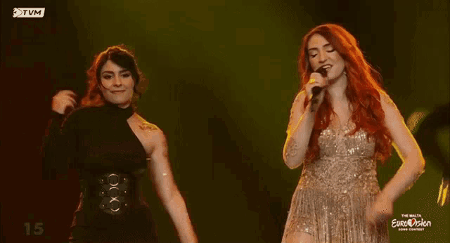 a woman singing into a microphone with the number 15 on the bottom of the screen