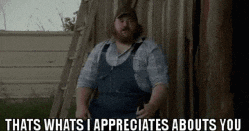 a man in overalls is standing in front of a wooden wall and says that 's whats i appreciate abouts you