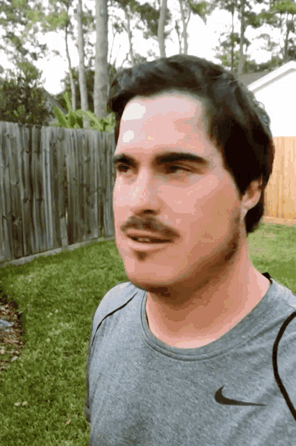 a man with a mustache wearing a nike shirt
