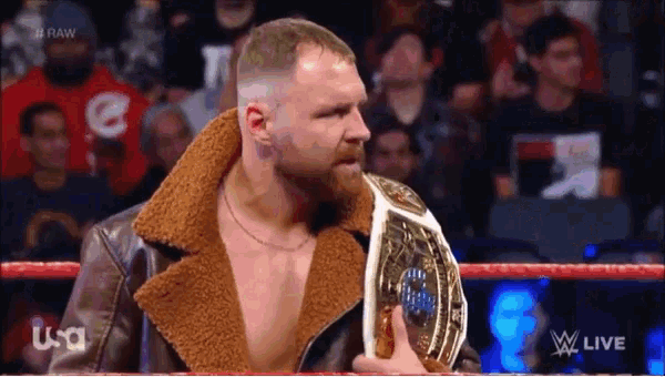 a man in a leather jacket is holding a world heavyweight wrestling championship belt ..