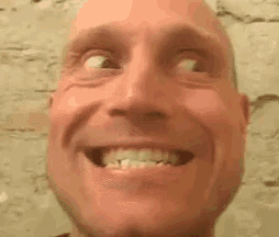 a close up of a bald man making a funny face with his eyes closed .
