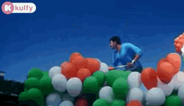 a man is standing in front of a pile of balloons .
