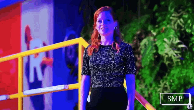a woman in a black top and black skirt is standing next to a railing .