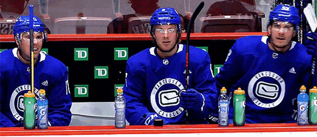 three hockey players wearing blue jerseys with the letter g on the front