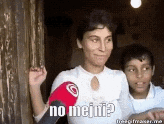 a woman is holding a microphone in front of her chest and says no mejini .