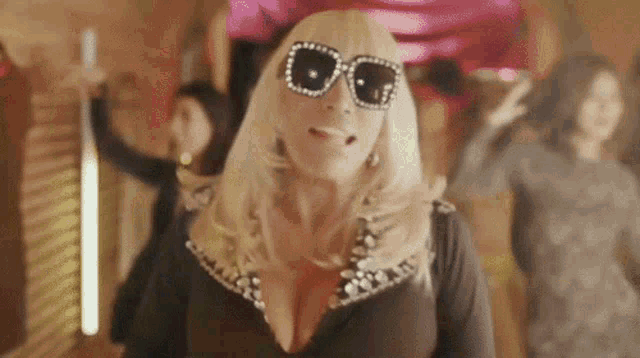 a woman wearing sunglasses and a wig is dancing in a room