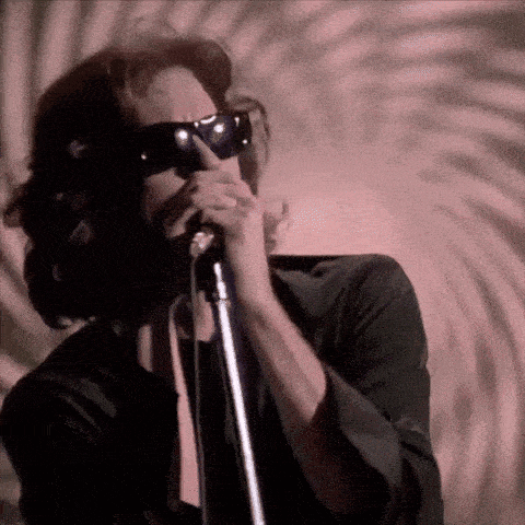 a man singing into a microphone with sunglasses on