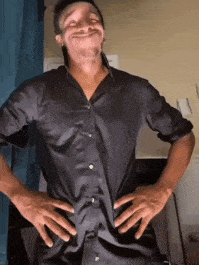 a man wearing a black shirt is making a funny face with his hands on his hips .