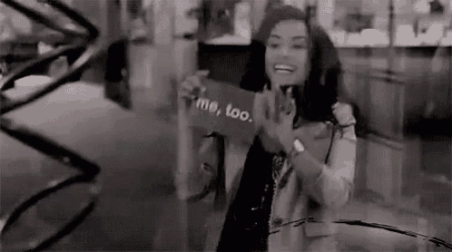 a woman is holding a sign that says `` me too '' in a black and white photo .