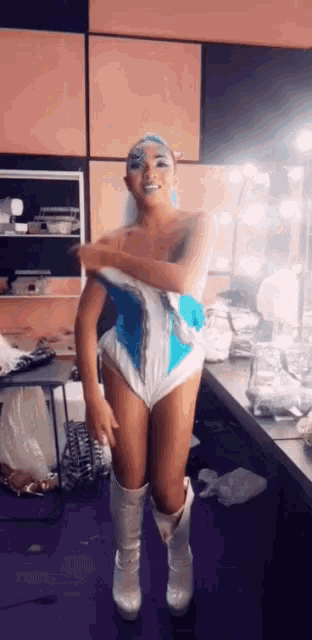 a woman in a blue and white costume is standing in a dressing room