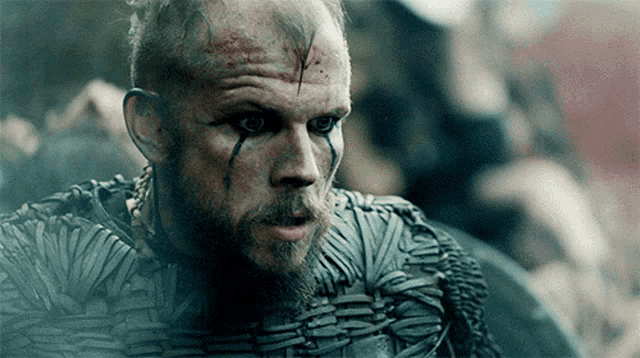 a man with a beard and blood on his face is wearing armor