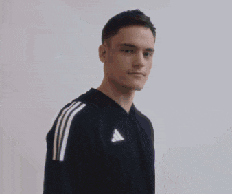 a young man wearing a black adidas t-shirt stands with his arms crossed