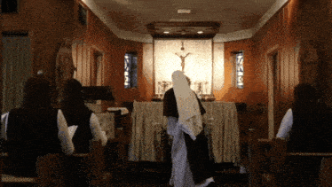 a woman in a white robe stands in front of an altar with a cross on it