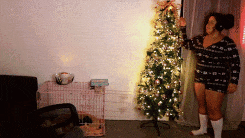 a woman standing in front of a christmas tree wearing shorts and socks