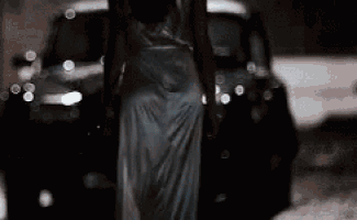 a car is driving down a snowy road at night with a person standing next to it .