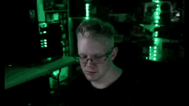 a man with glasses is talking on a cell phone in a dark room