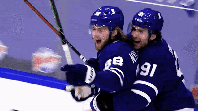 two hockey players one wearing the number 91 are hugging each other on the ice