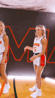 two female basketball players are standing next to each other on the court .