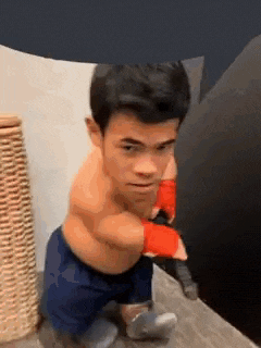 a very small man is standing on a wooden floor wearing boxing gloves and shorts .