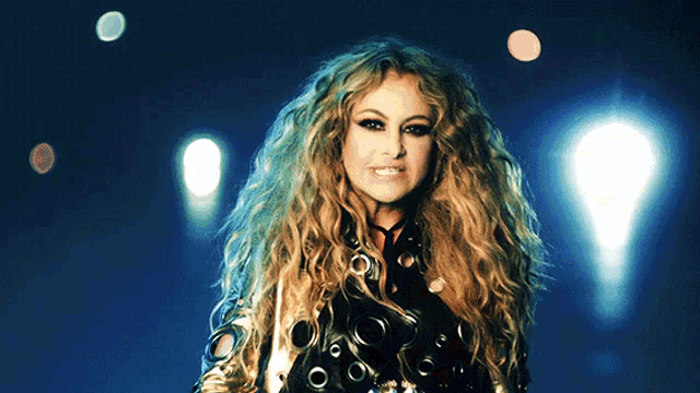 a woman with long curly hair is standing in front of lights