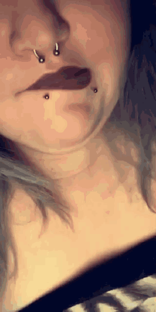 a close up of a woman 's face with a nose ring and lip piercings