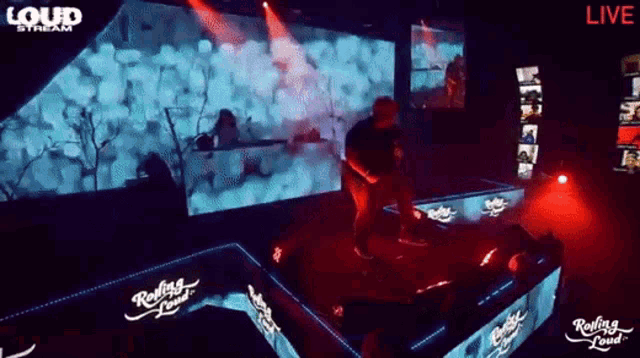 a man is dancing on a stage in front of a loud stream sign